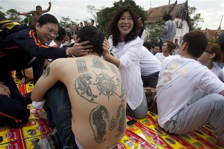 A foreign tourist has his tattoos admired during a tattoo festival at Wat Bang Pra in Nakhon Chaisi, Thailand. 